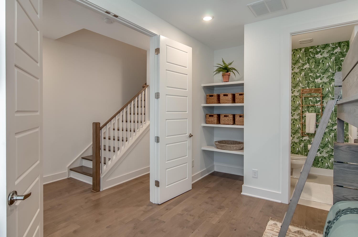 Modern hallway with staircase and shelves.