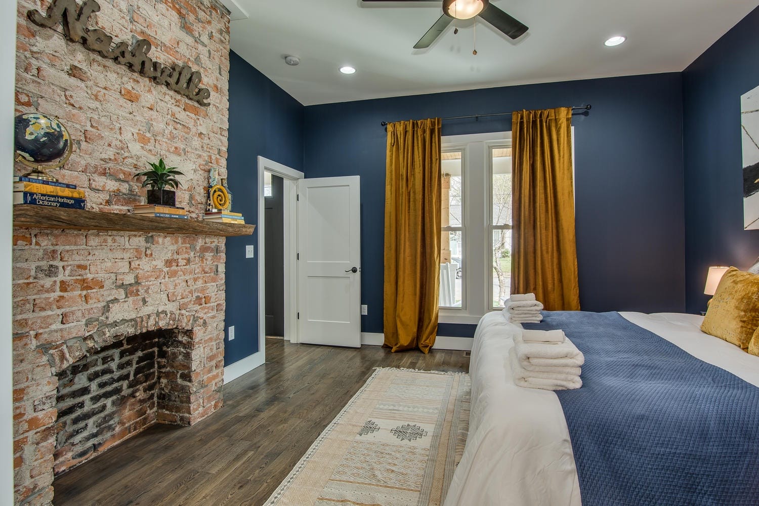 Modern bedroom with exposed brick fireplace.