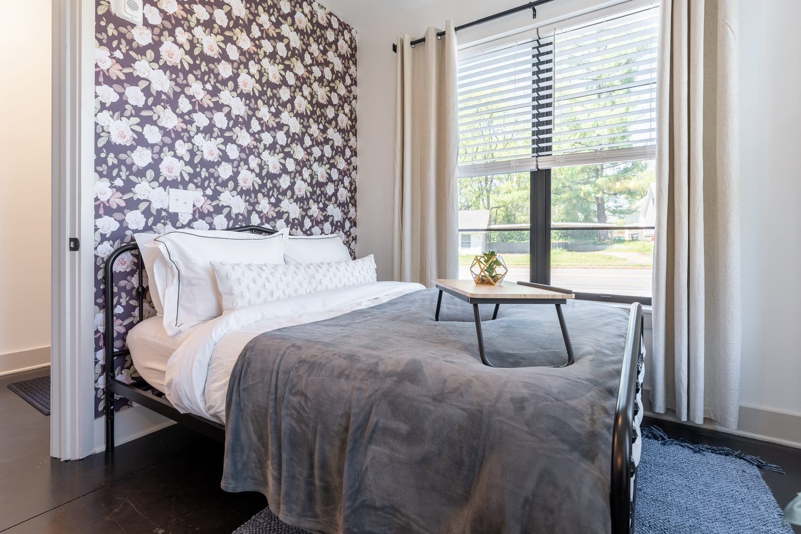 Bedroom with floral wallpaper and bed.