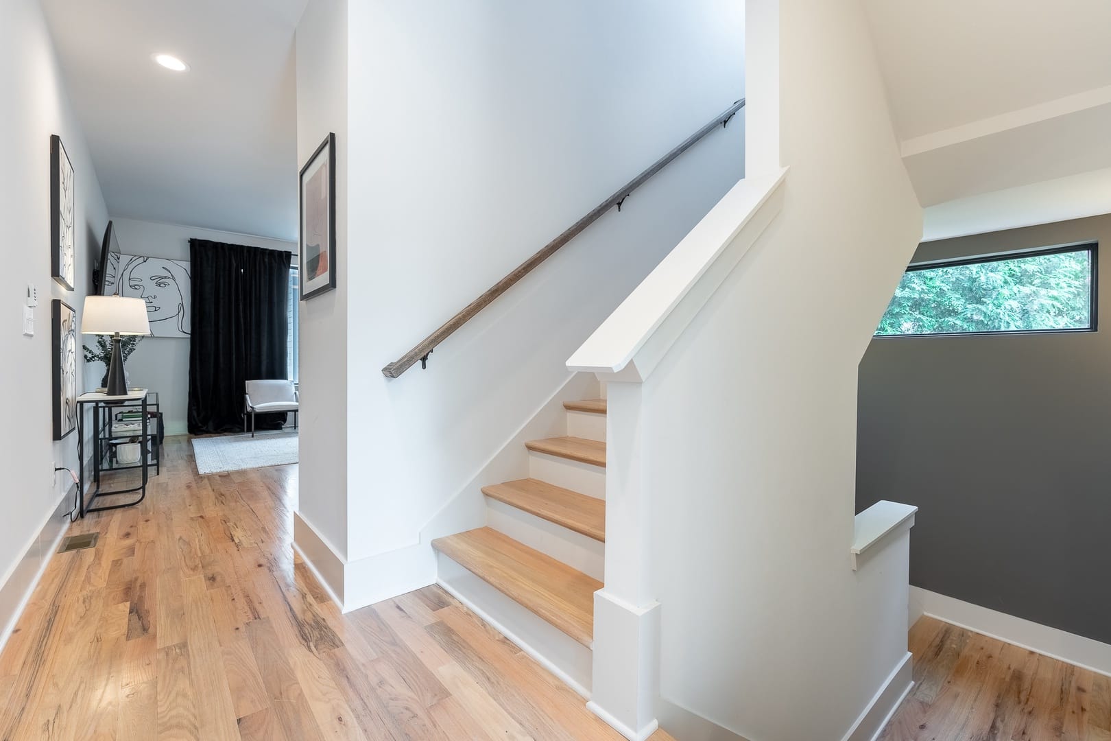 Modern hallway with staircase and artwork.