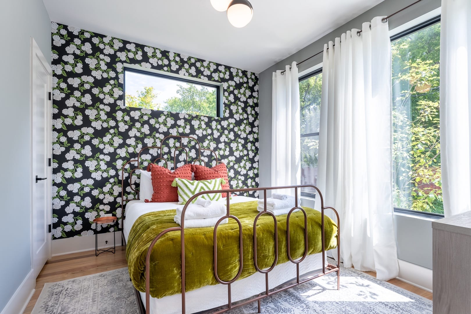 Bright bedroom with floral accent wall.