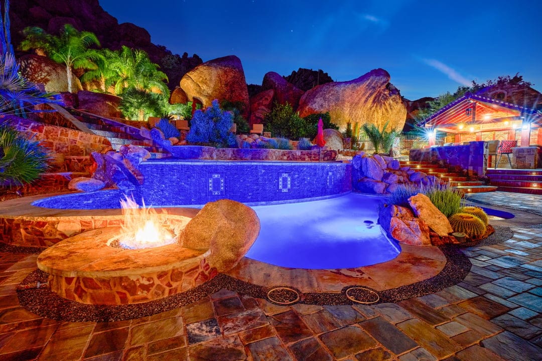 Illuminated pool with fire pit.