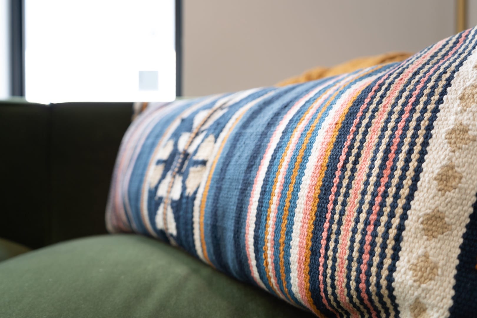 Colorful patterned pillow on green sofa.