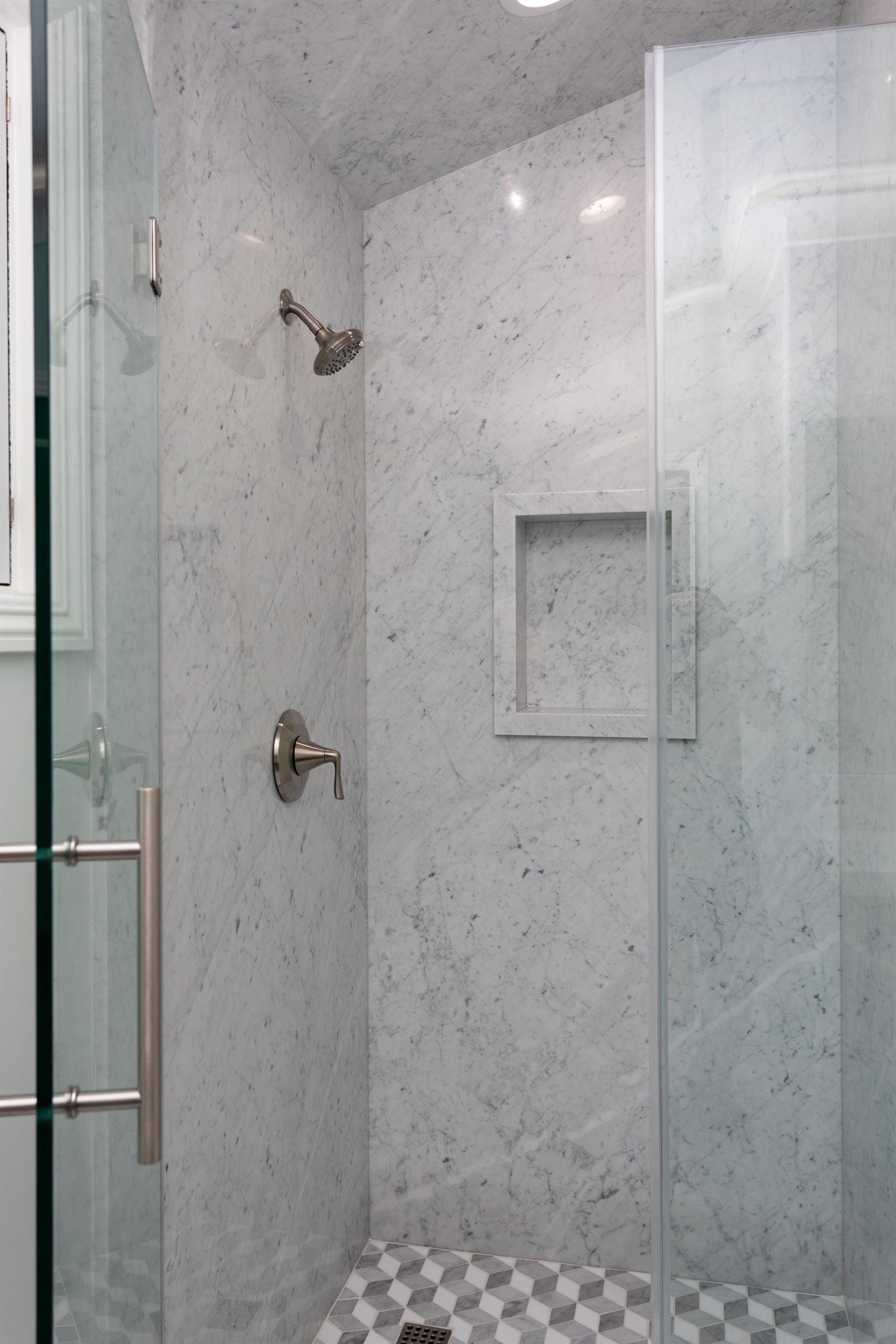 Marble-tiled shower with glass door.