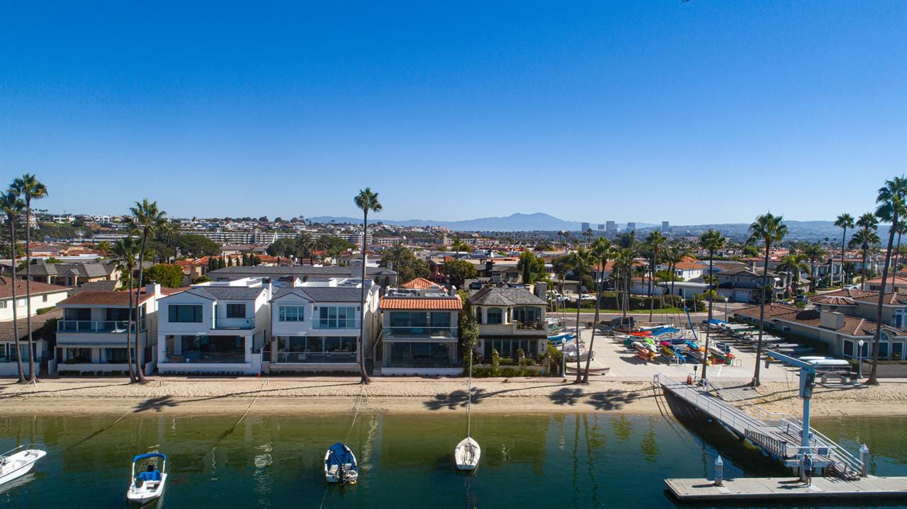 Waterfront homes with boats, palm trees.