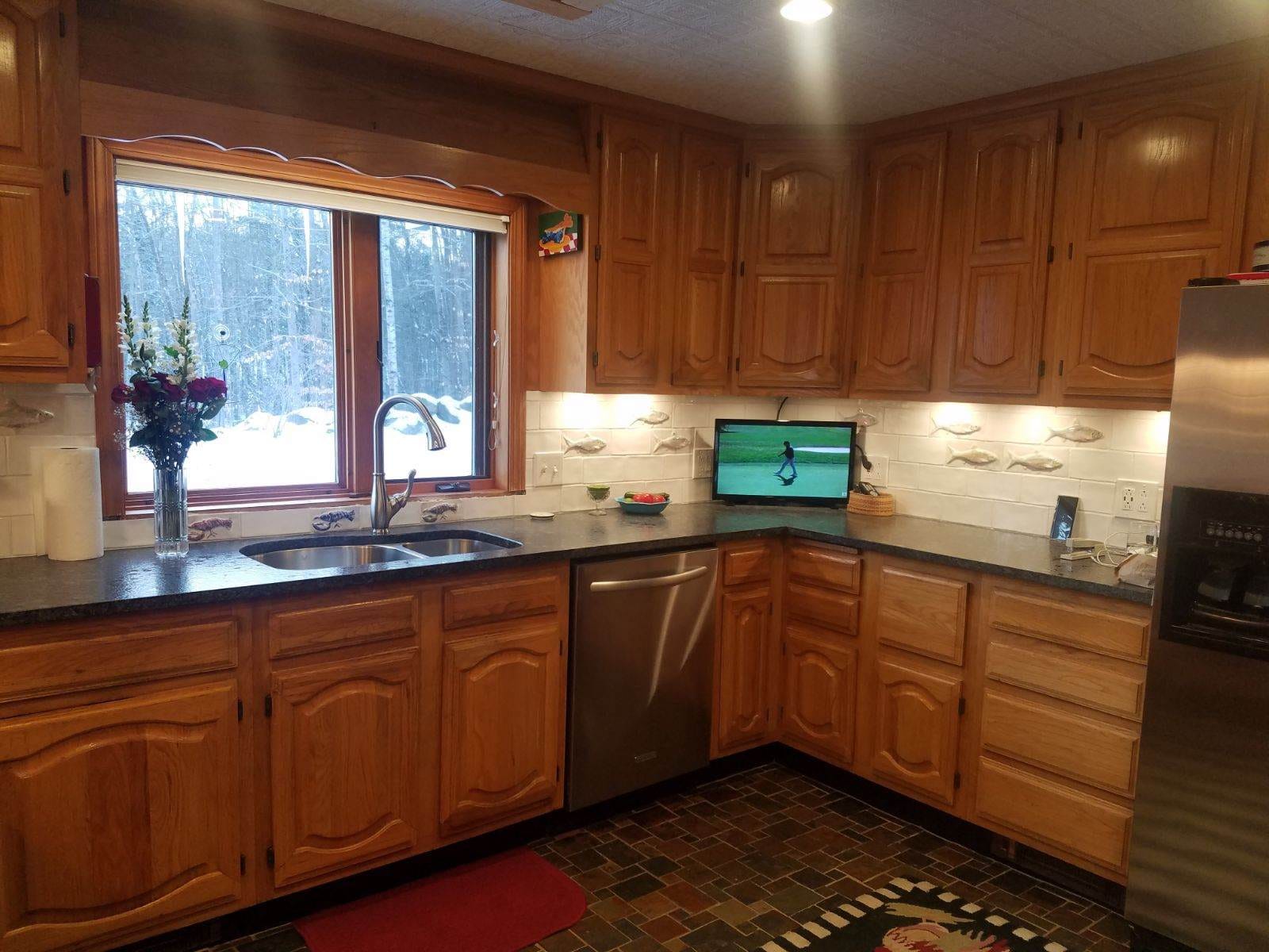 Wooden kitchen with window, TV, sink.