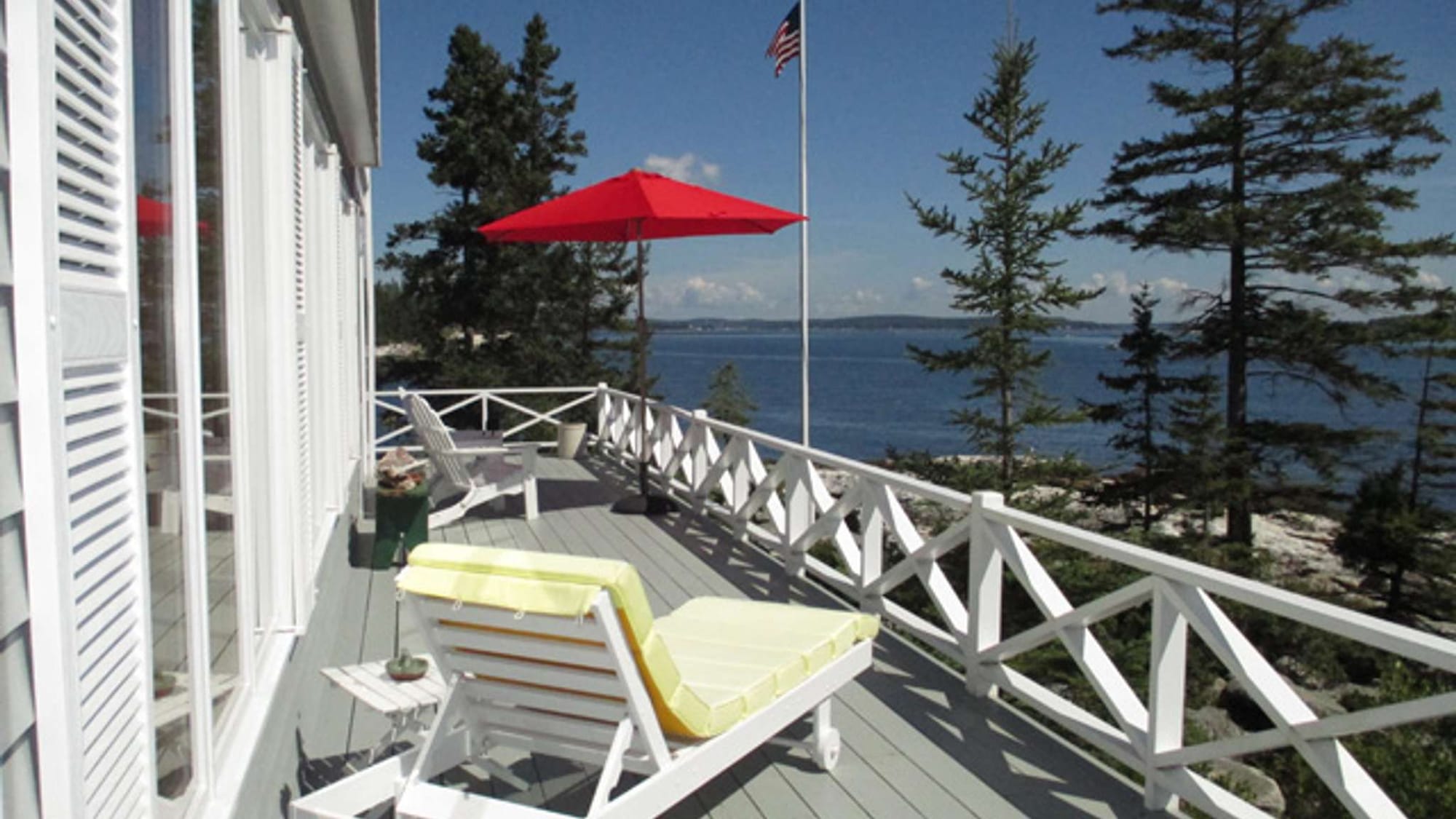 Deck overlooking lake with red umbrella.