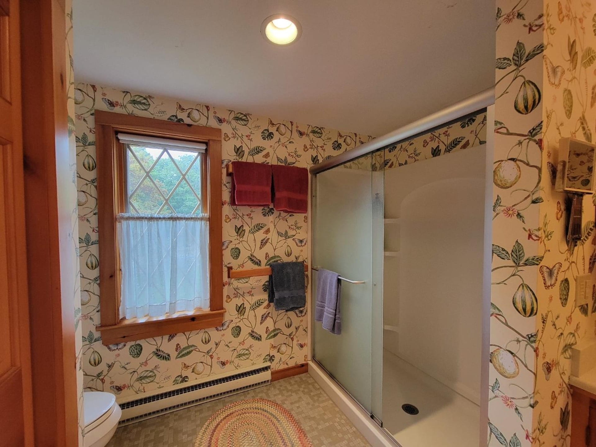 Floral wallpapered bathroom with shower.