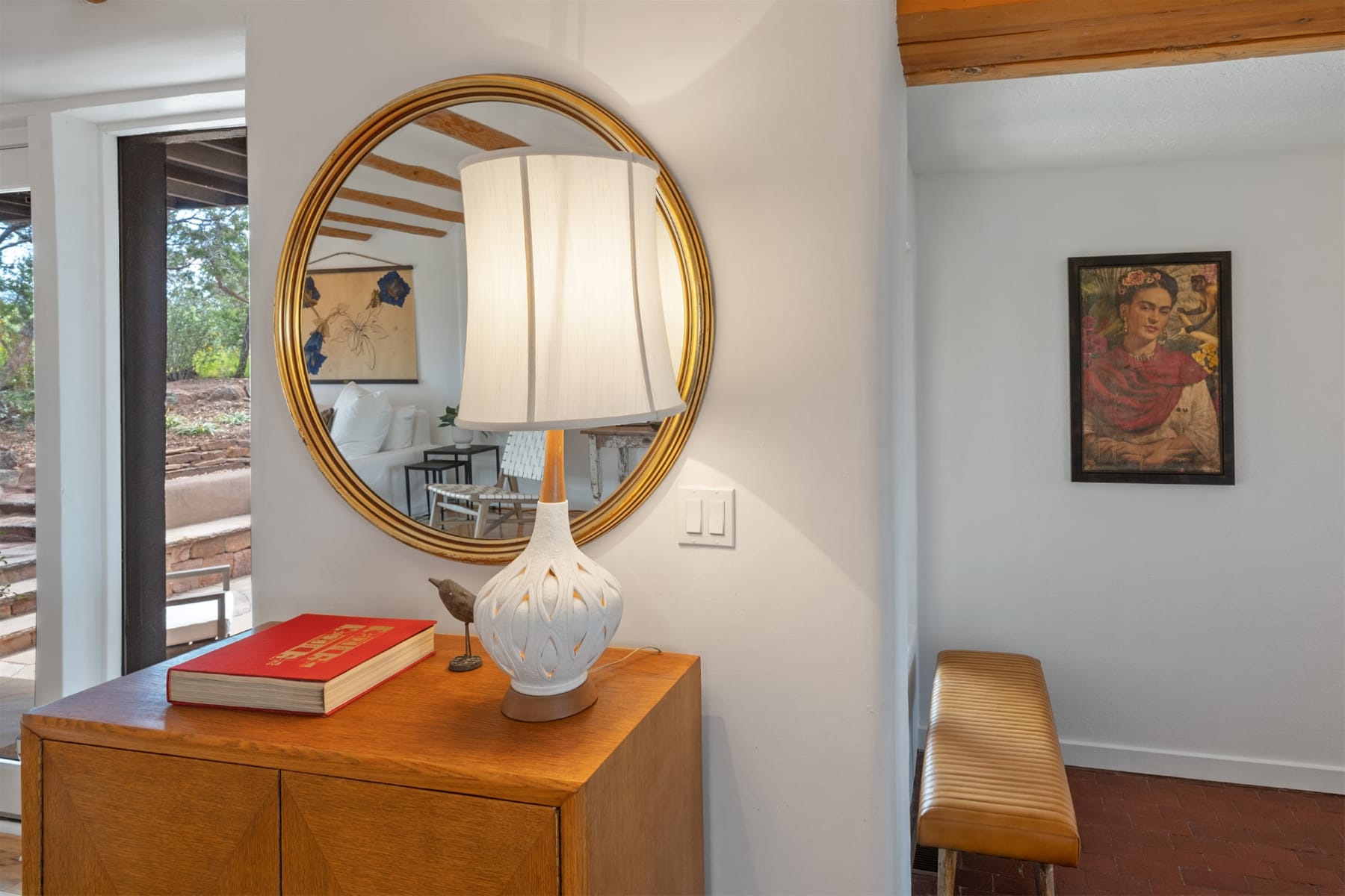 Round mirror above wooden cabinet.