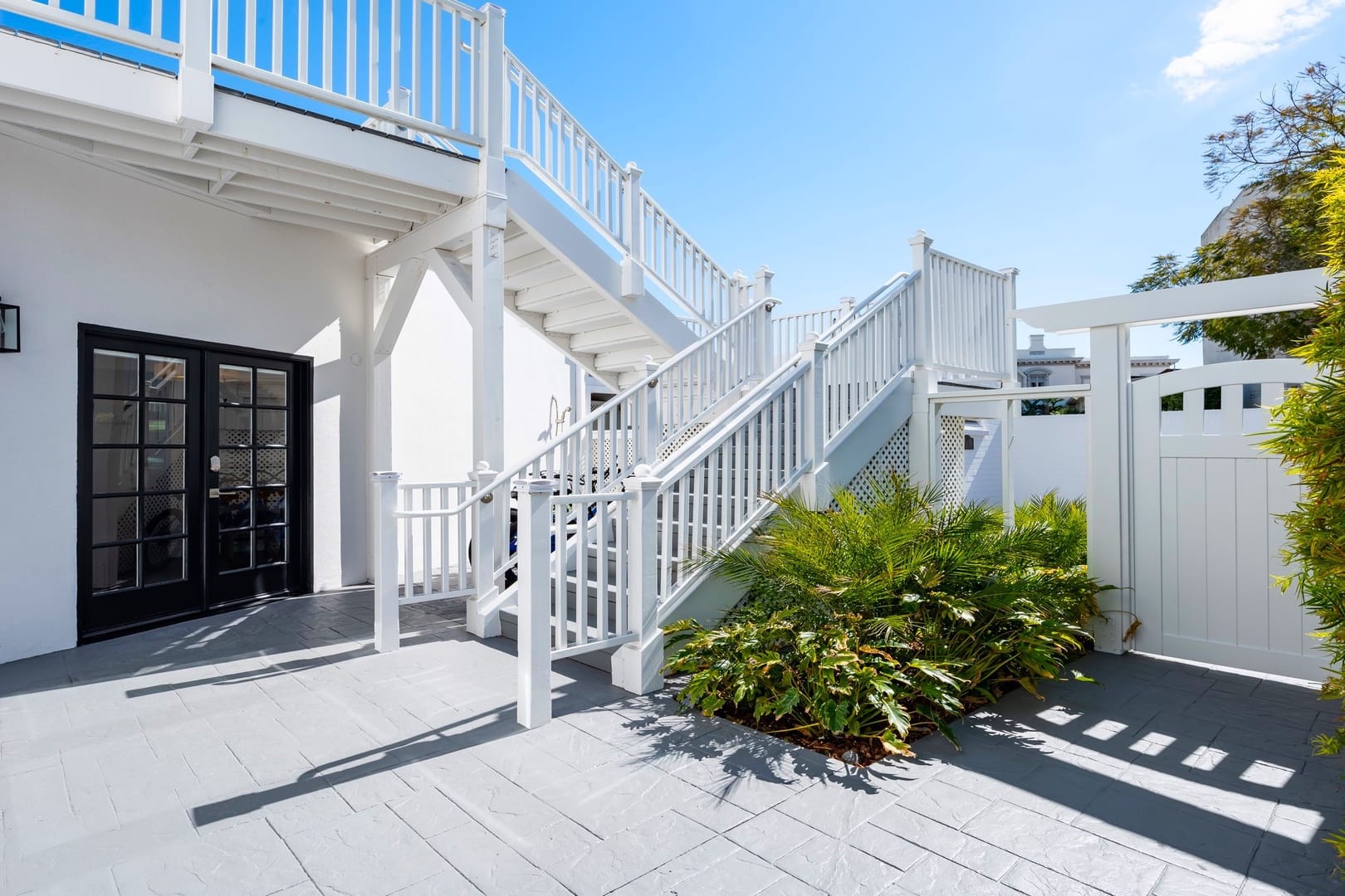 White exterior stairs with greenery.