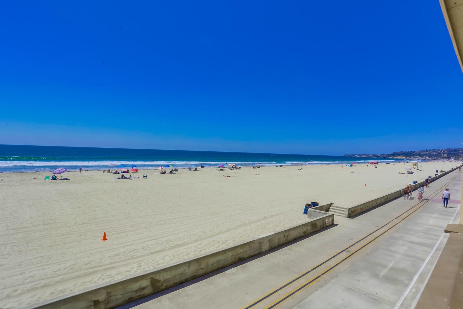 Sandy beach with umbrellas and ocean.