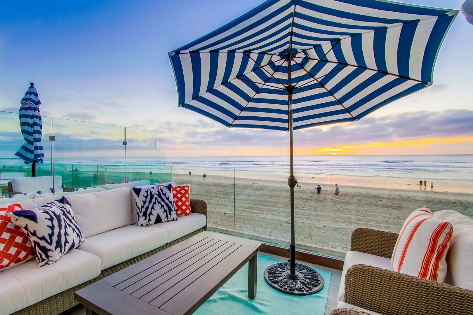 Beachfront patio with striped umbrella.