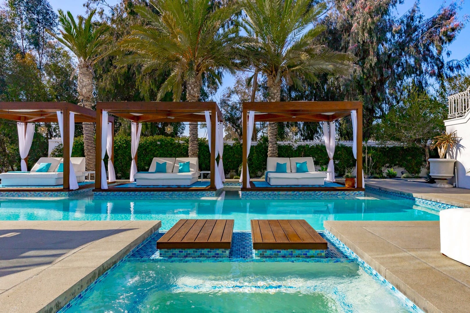 Luxurious poolside cabanas with palms.