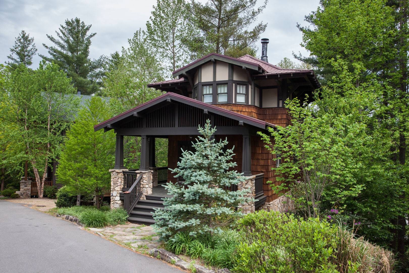 House with porch surrounded by trees.