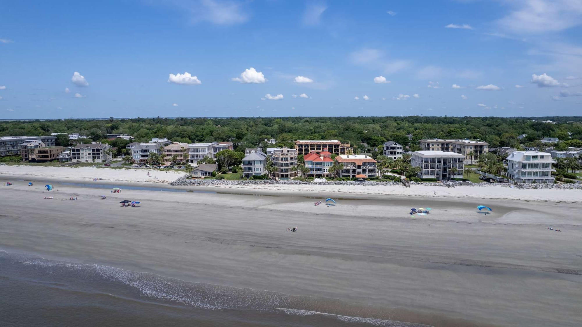 Beachfront homes with people, umbrellas.