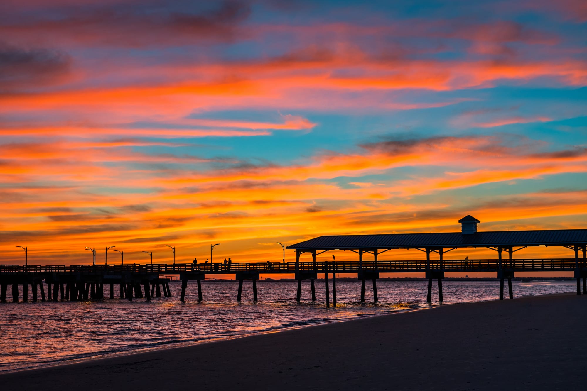 Sunset over pier with colorful sky.