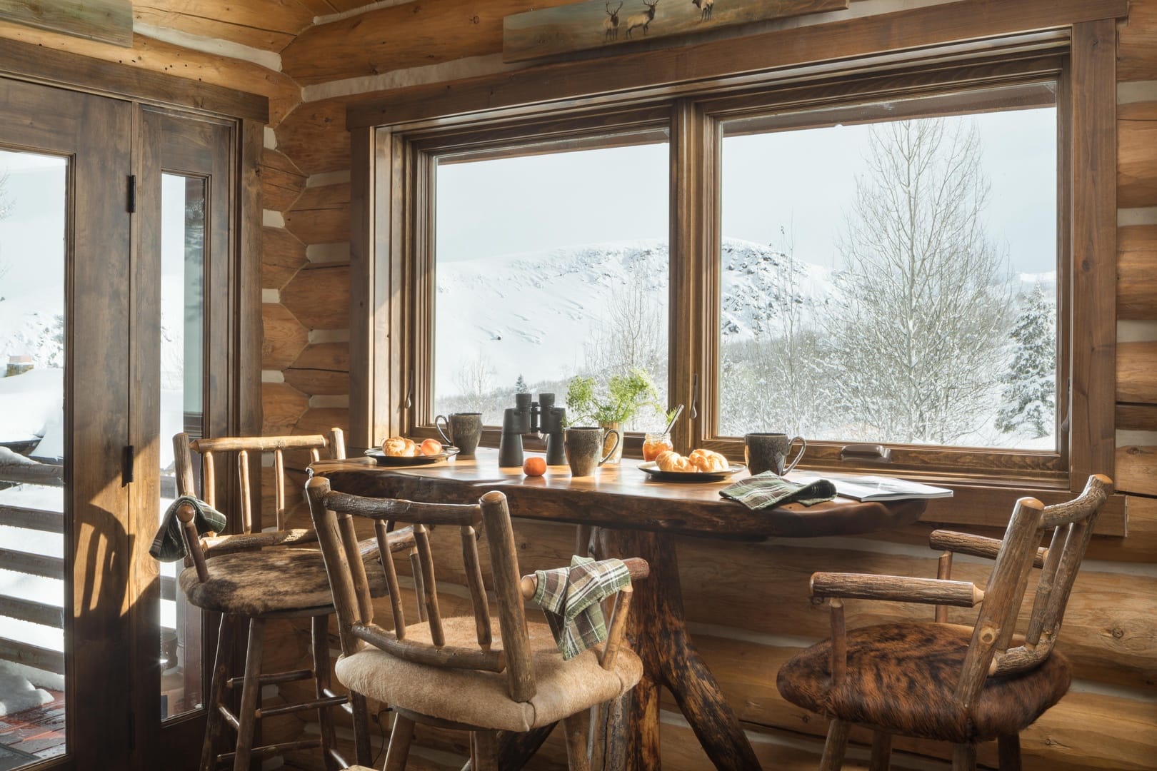 Cozy cabin dining area, snow outside.