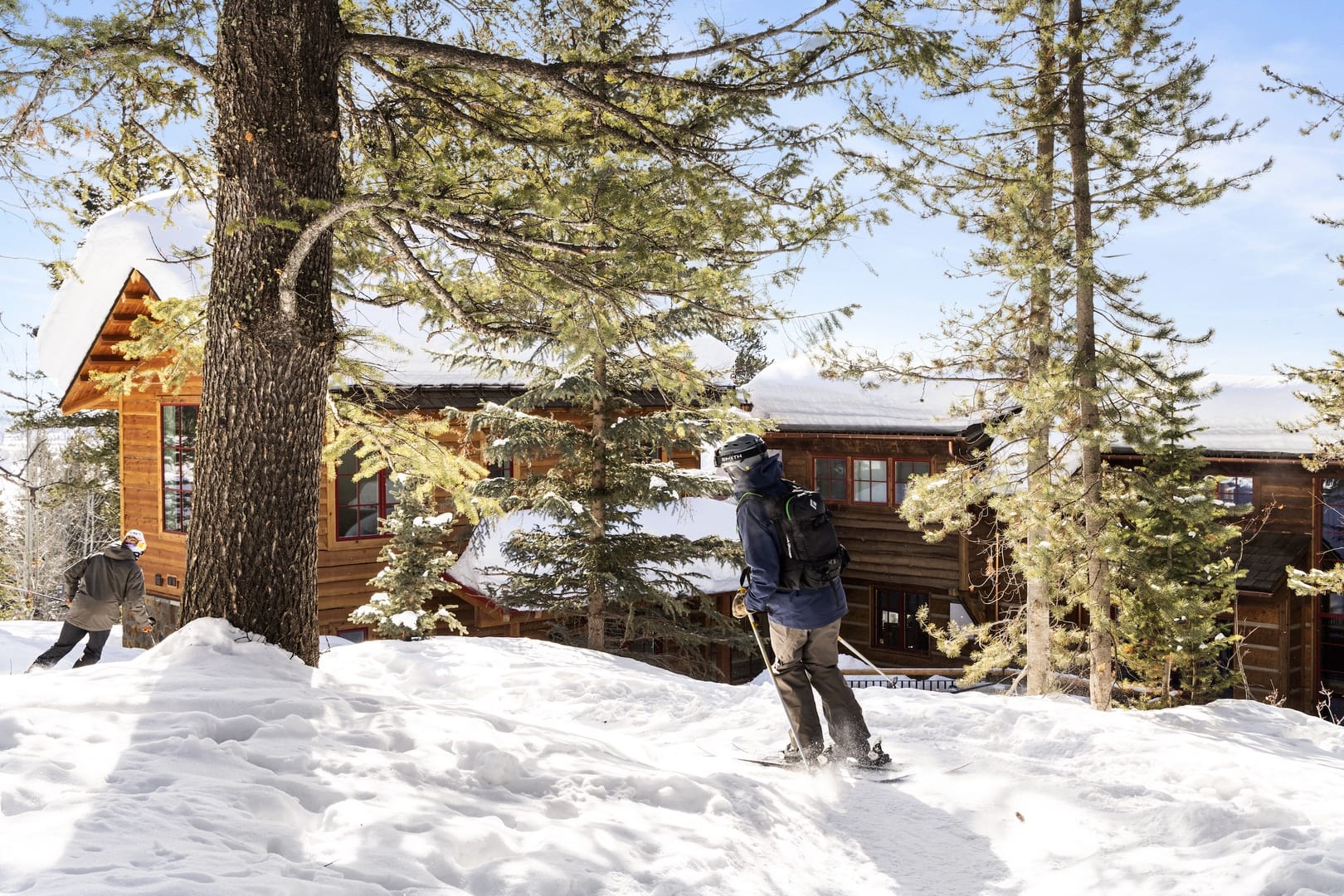 Skiers near a snowy cabin.