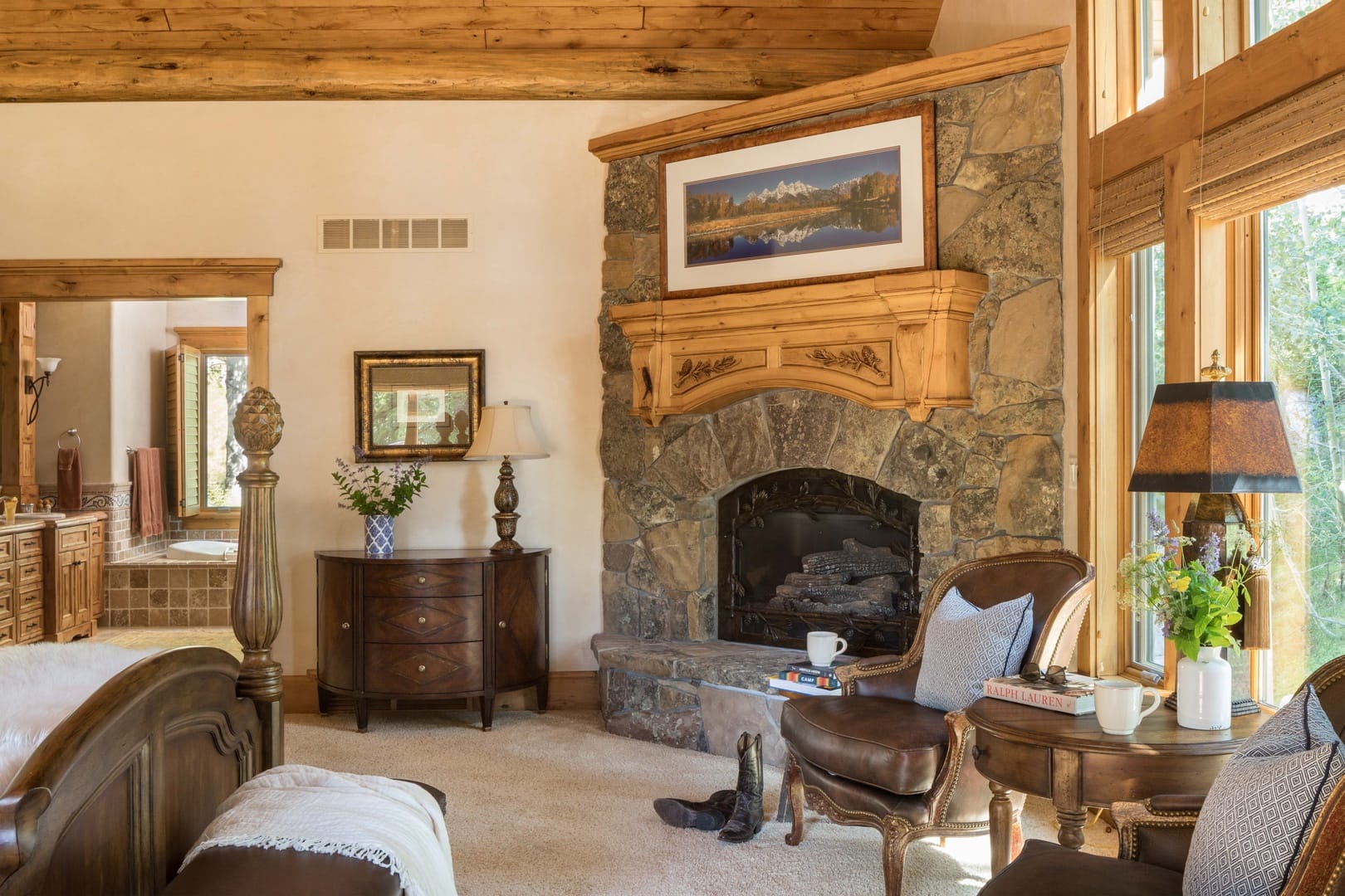 Rustic bedroom with stone fireplace.