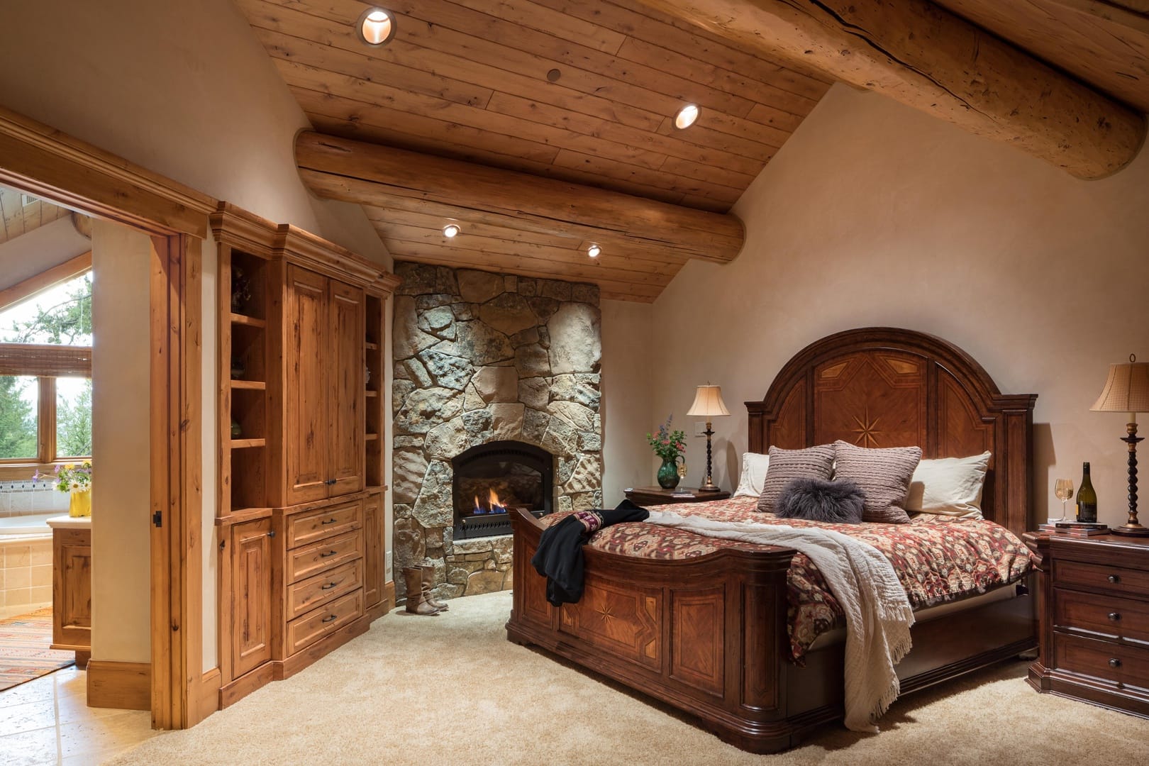 Rustic bedroom with stone fireplace.