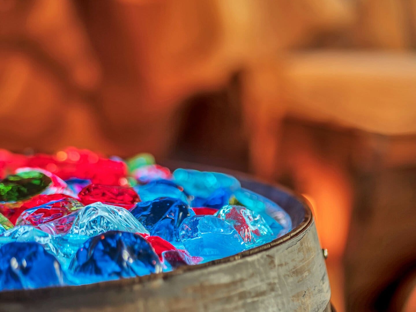 Colorful glass gems in wooden barrel.