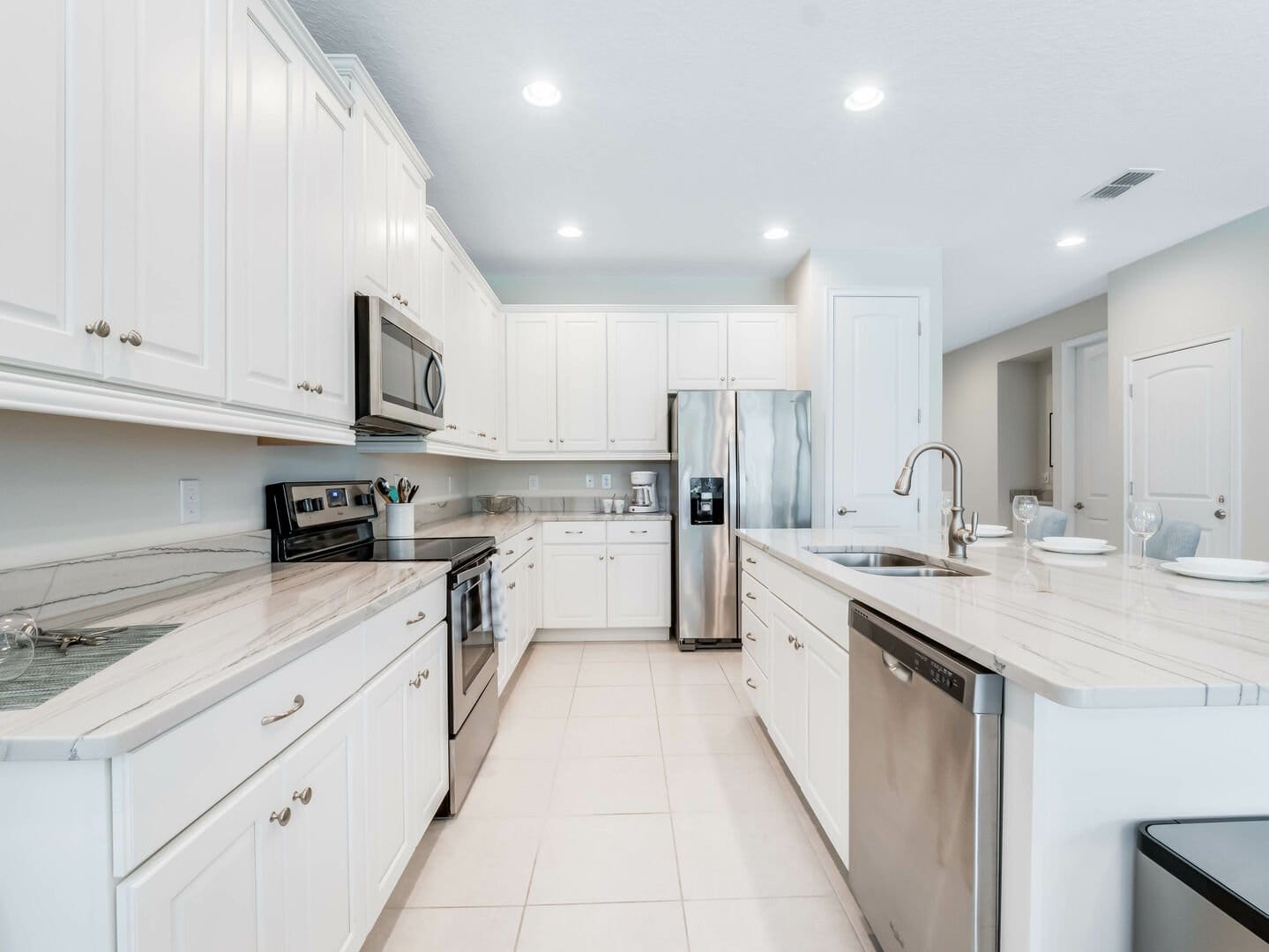 Modern white kitchen with stainless appliances.