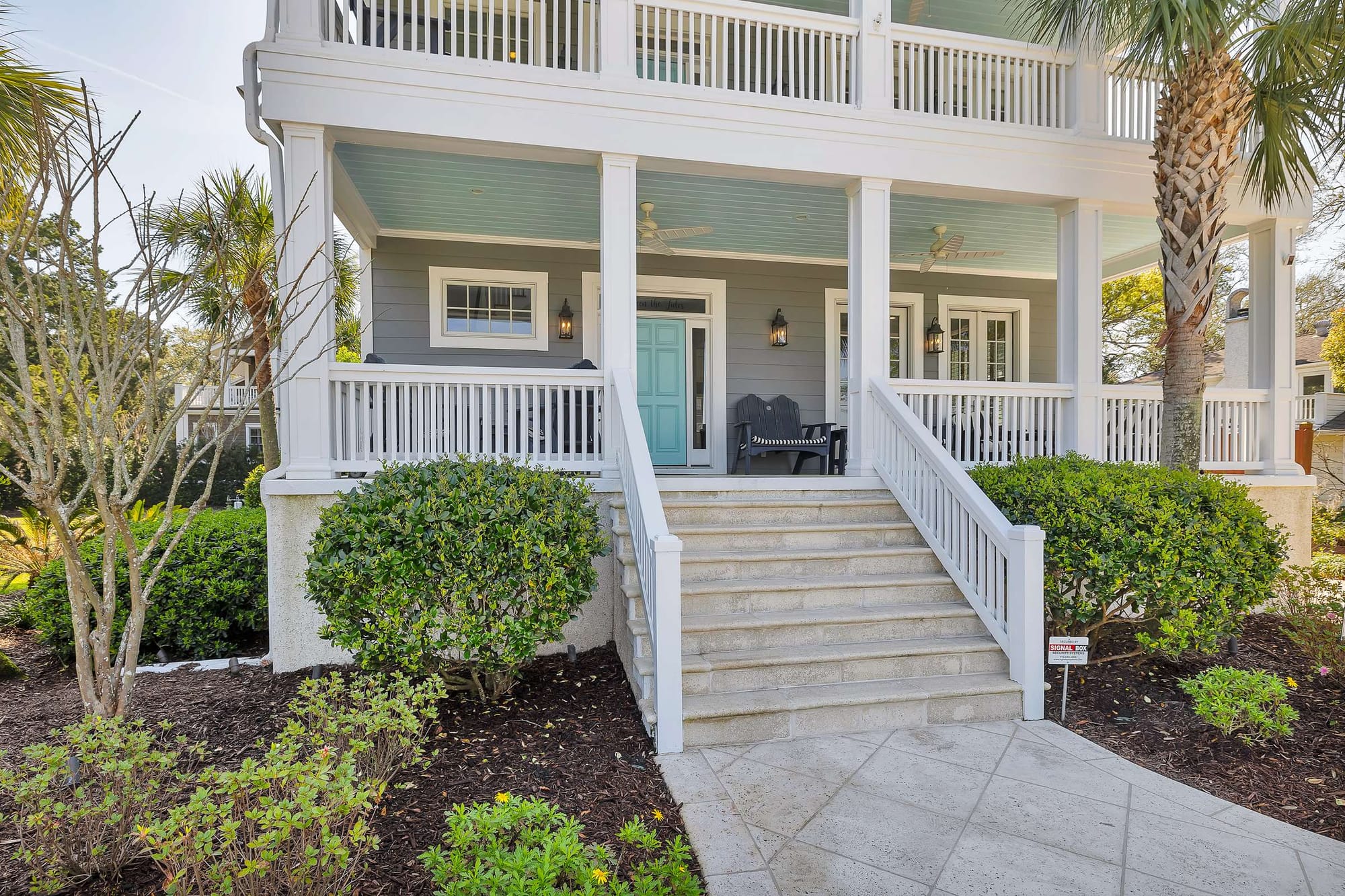 Two-story porch with pastel door.