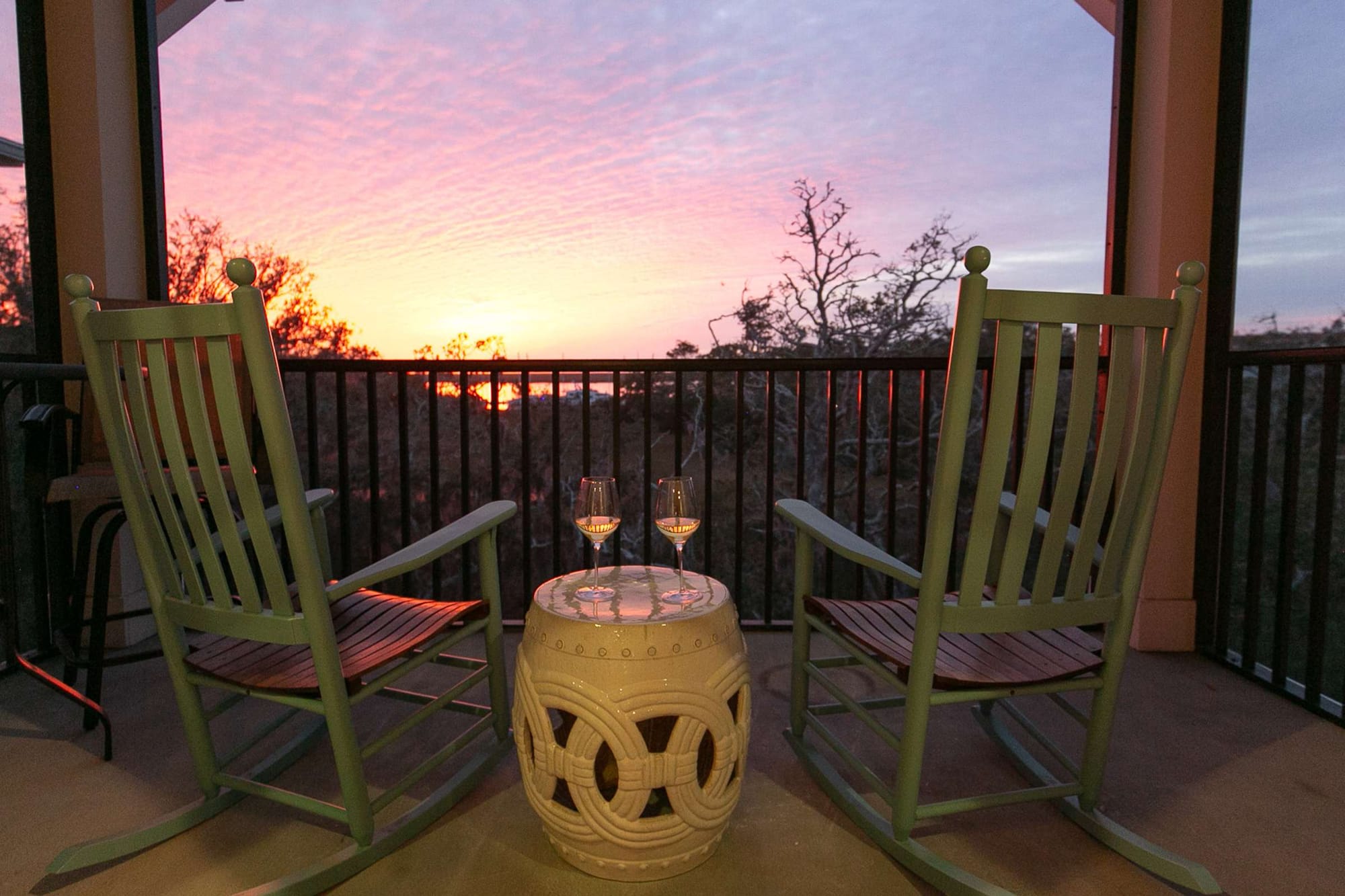 Rocking chairs facing sunset, balcony.