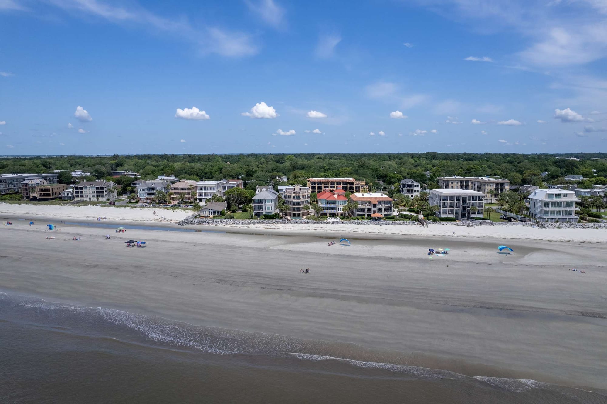 Beachfront houses with sandy shoreline.