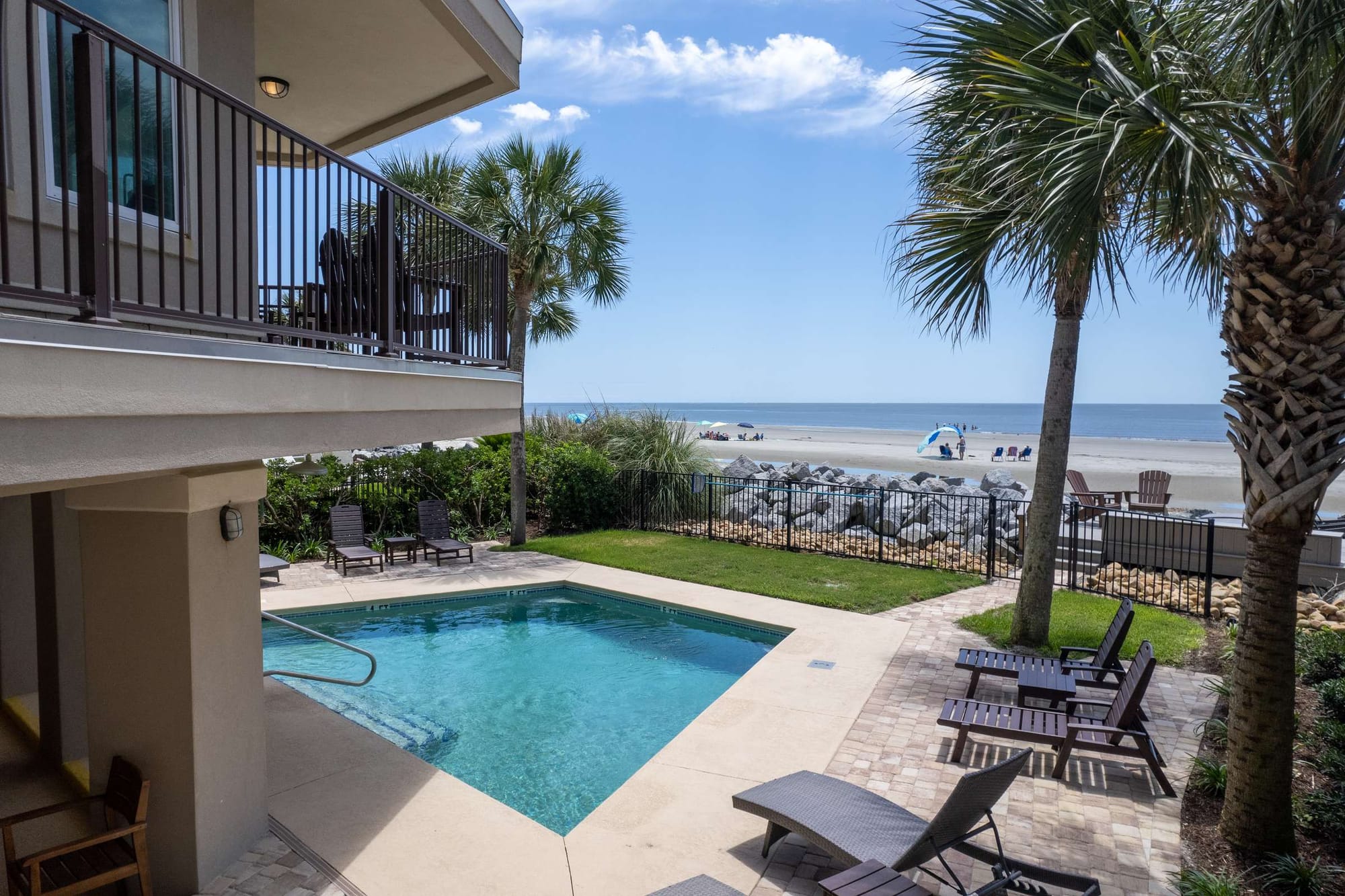 Pool overlooking beach with palm trees.