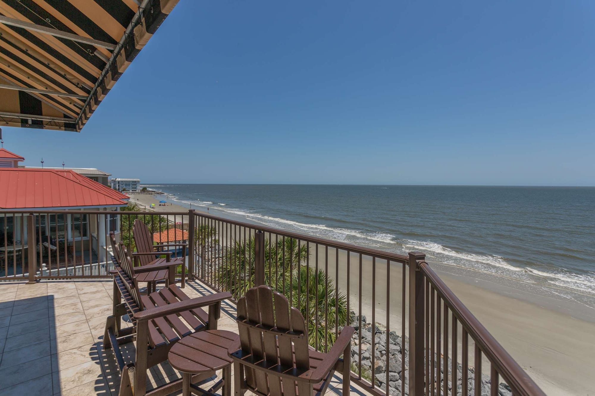 Beachfront balcony with wooden chairs.