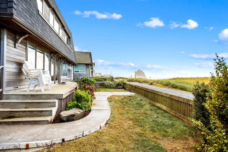 Beach house with patio and lawn.