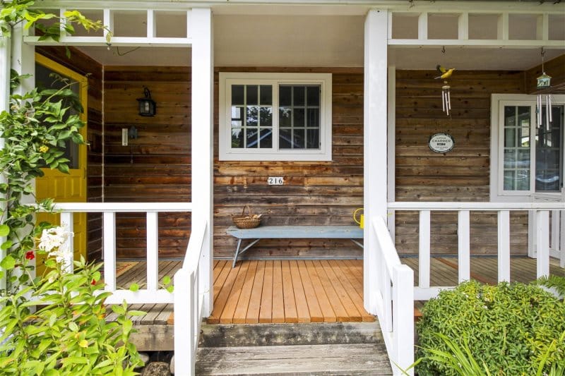 Wooden porch with bench and plants.