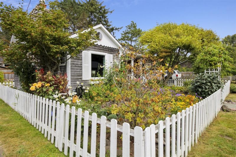 Cottage with garden behind fence.