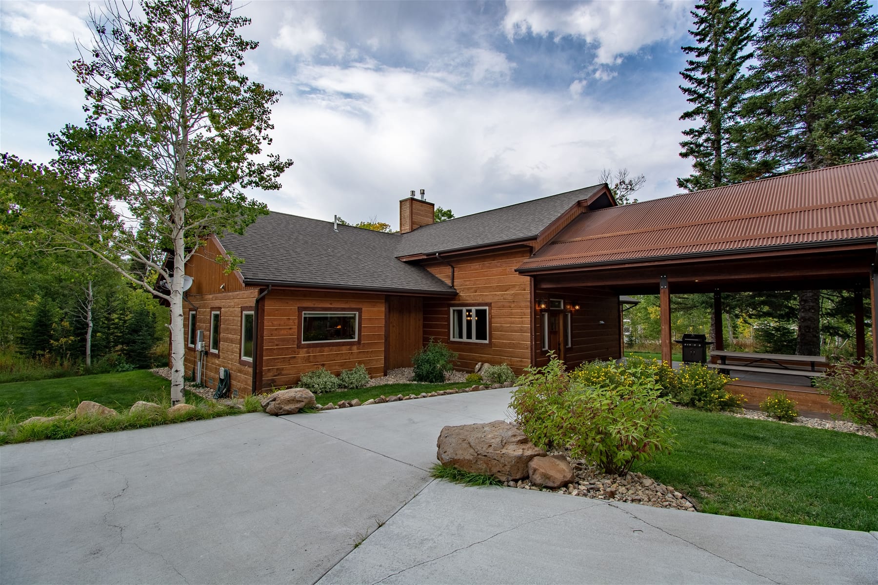 Wooden house with driveway, greenery.