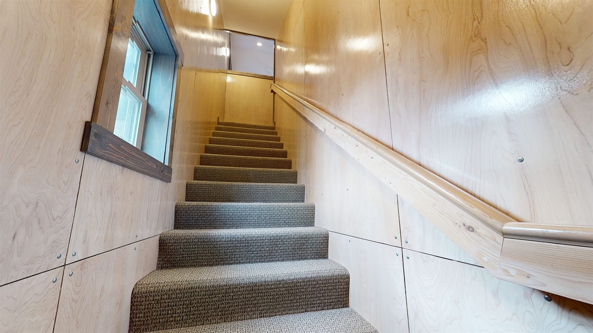 Carpeted stairs with wooden walls.