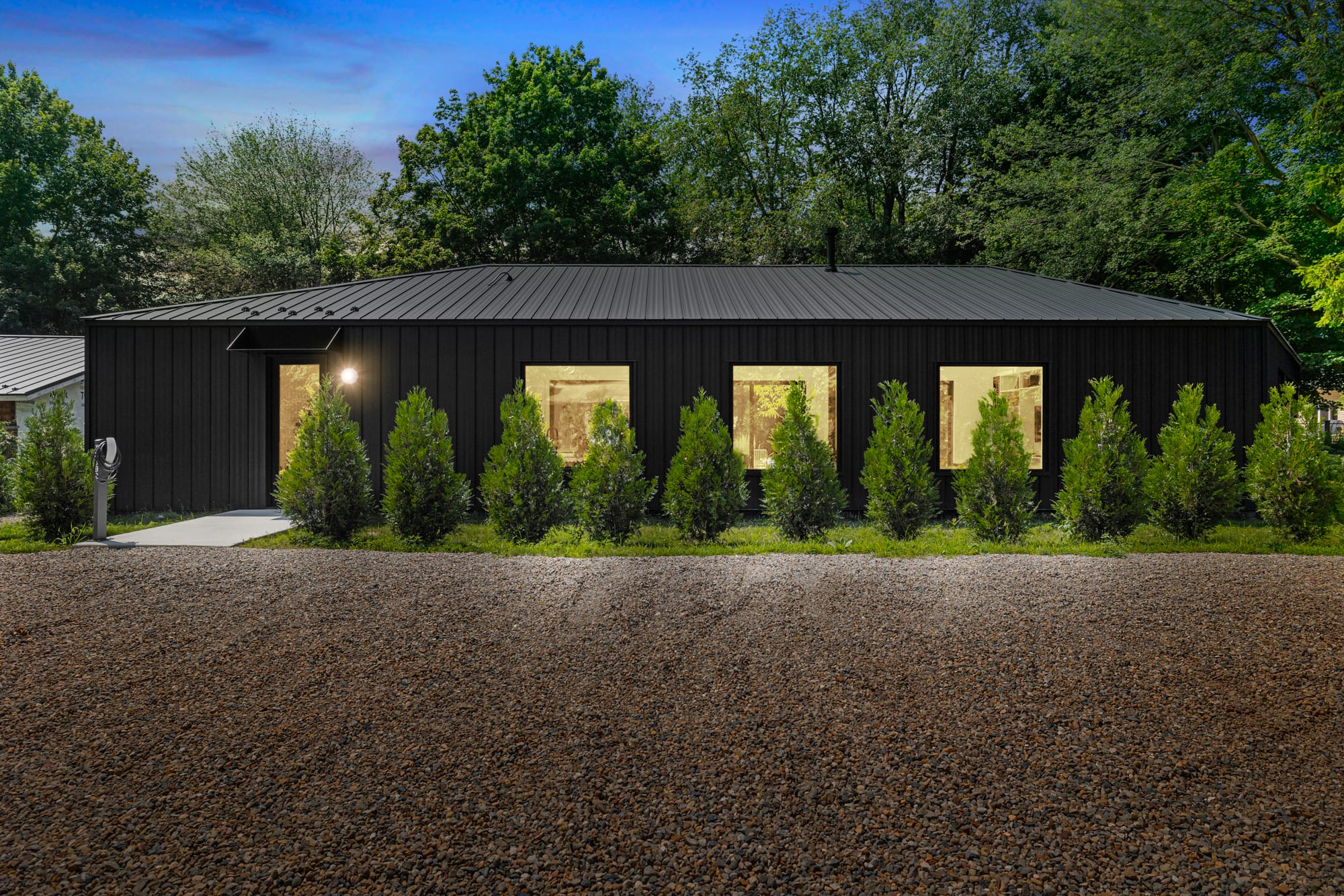 Modern black home with trees in front.