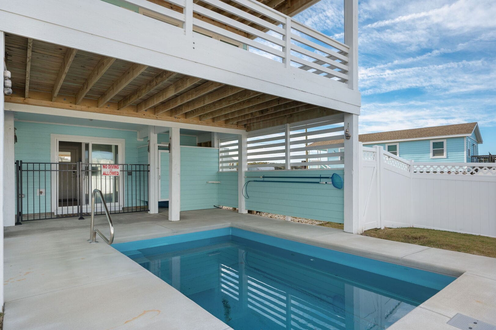 Covered outdoor pool by blue house.