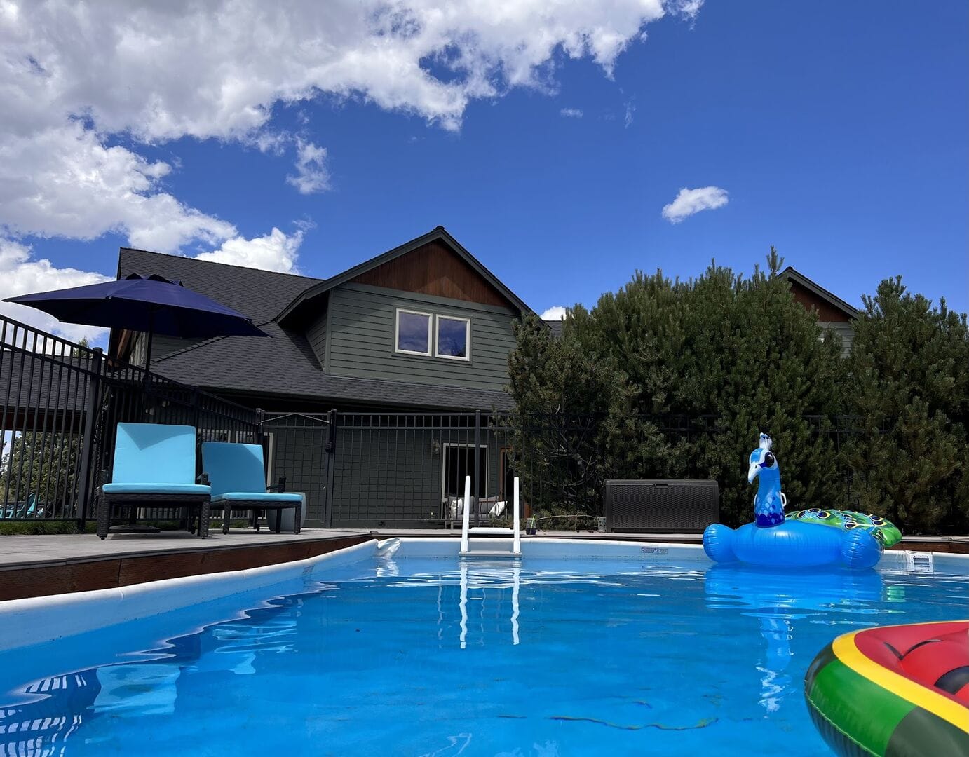 Backyard pool with house, furniture.