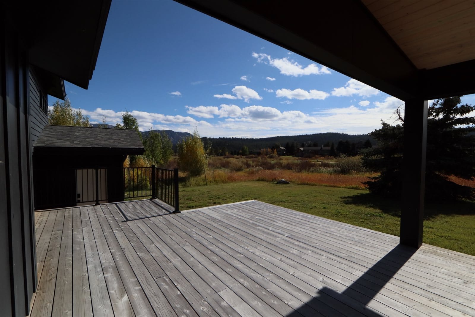 Wooden deck overlooking grassy, mountainous landscape.