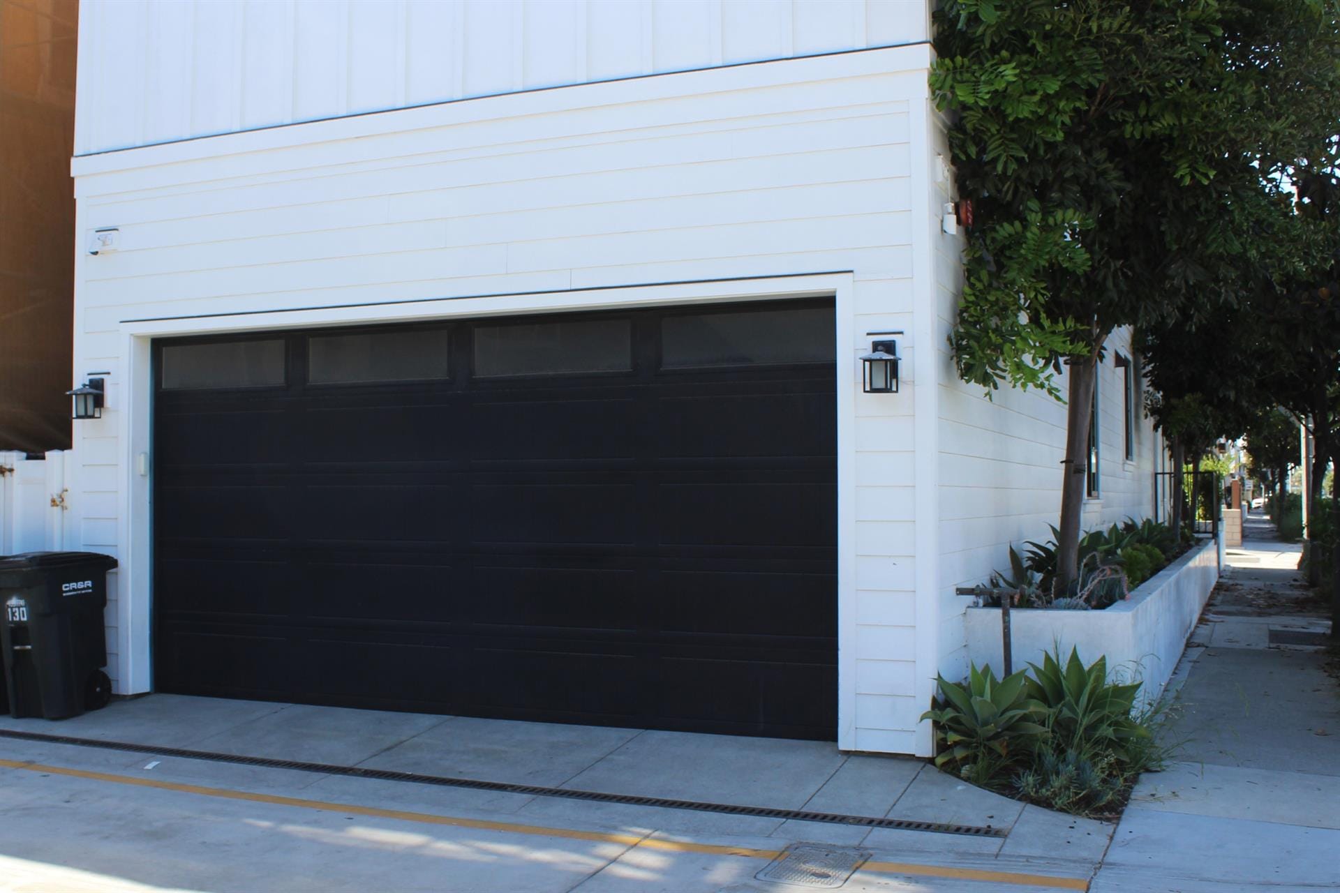 Black garage door, white house exterior.