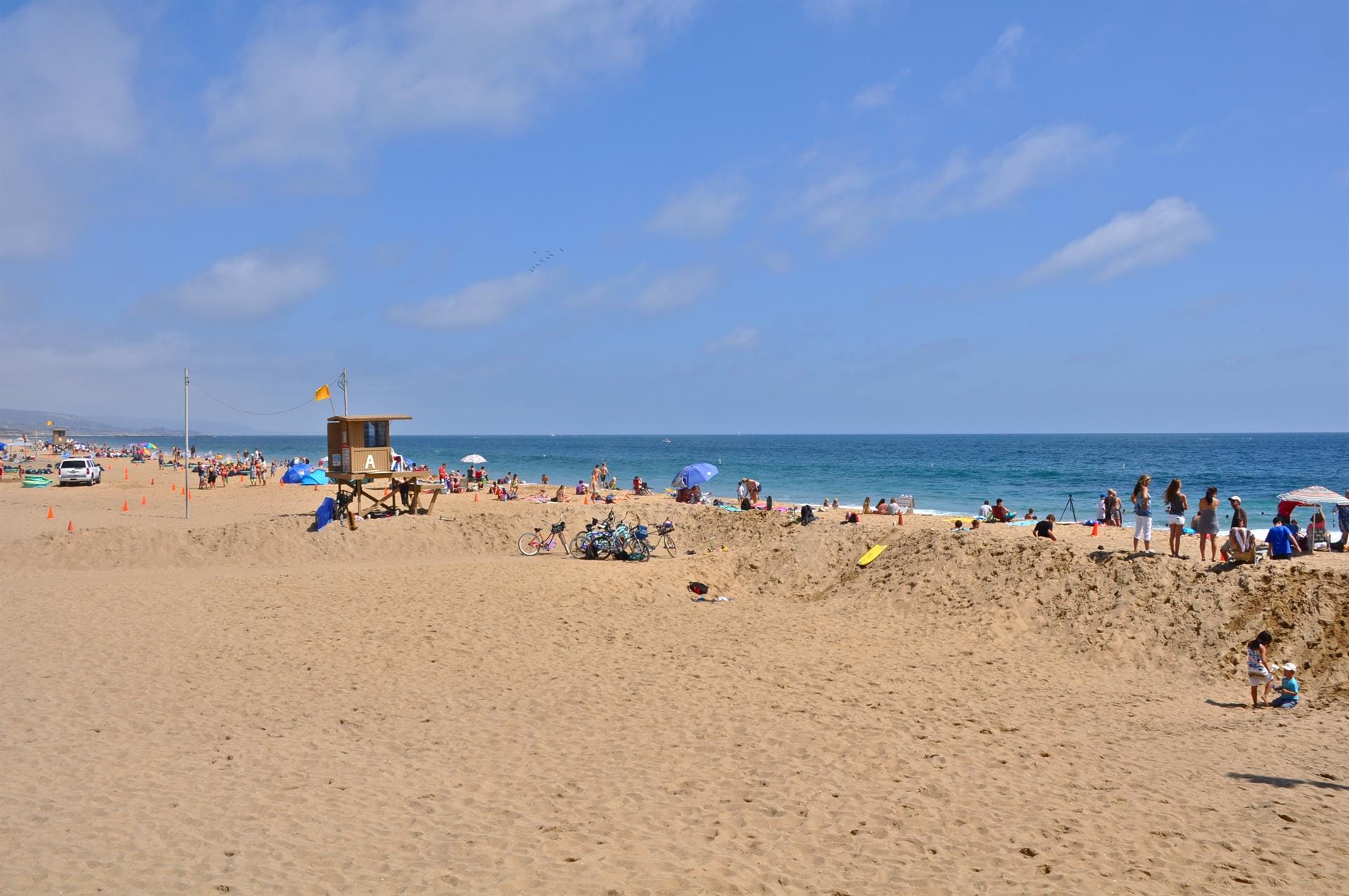 Crowded beach with lifeguard tower.