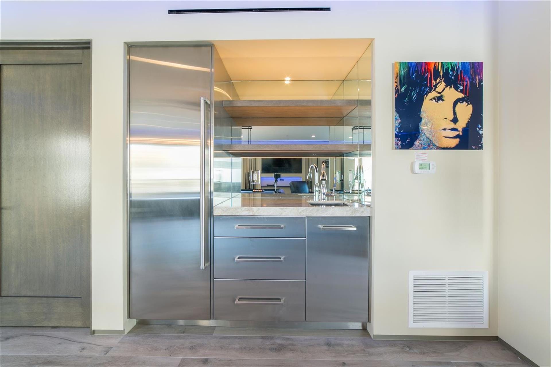 Modern kitchenette with colorful portrait.