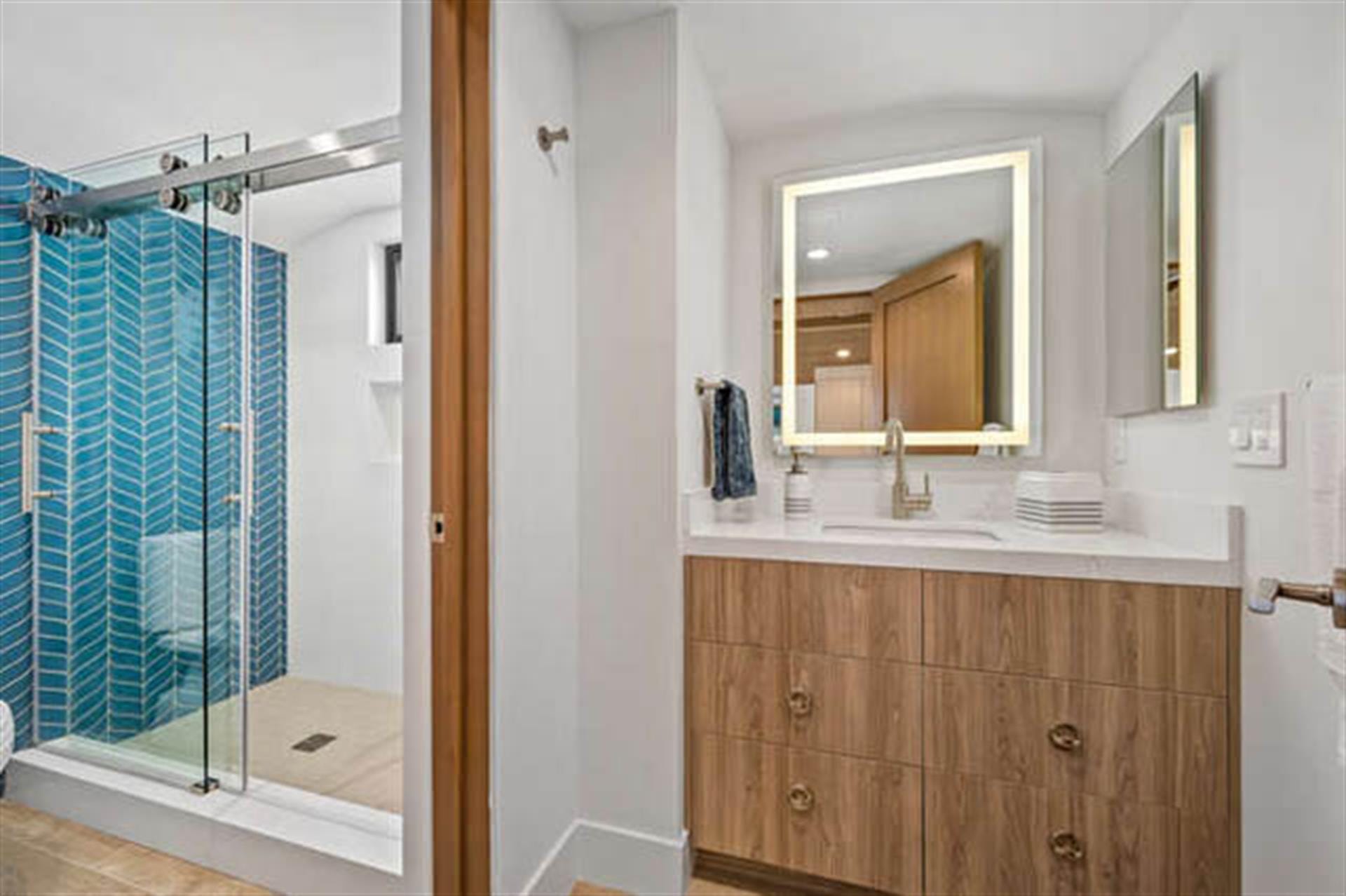 Modern bathroom with blue-tiled shower.