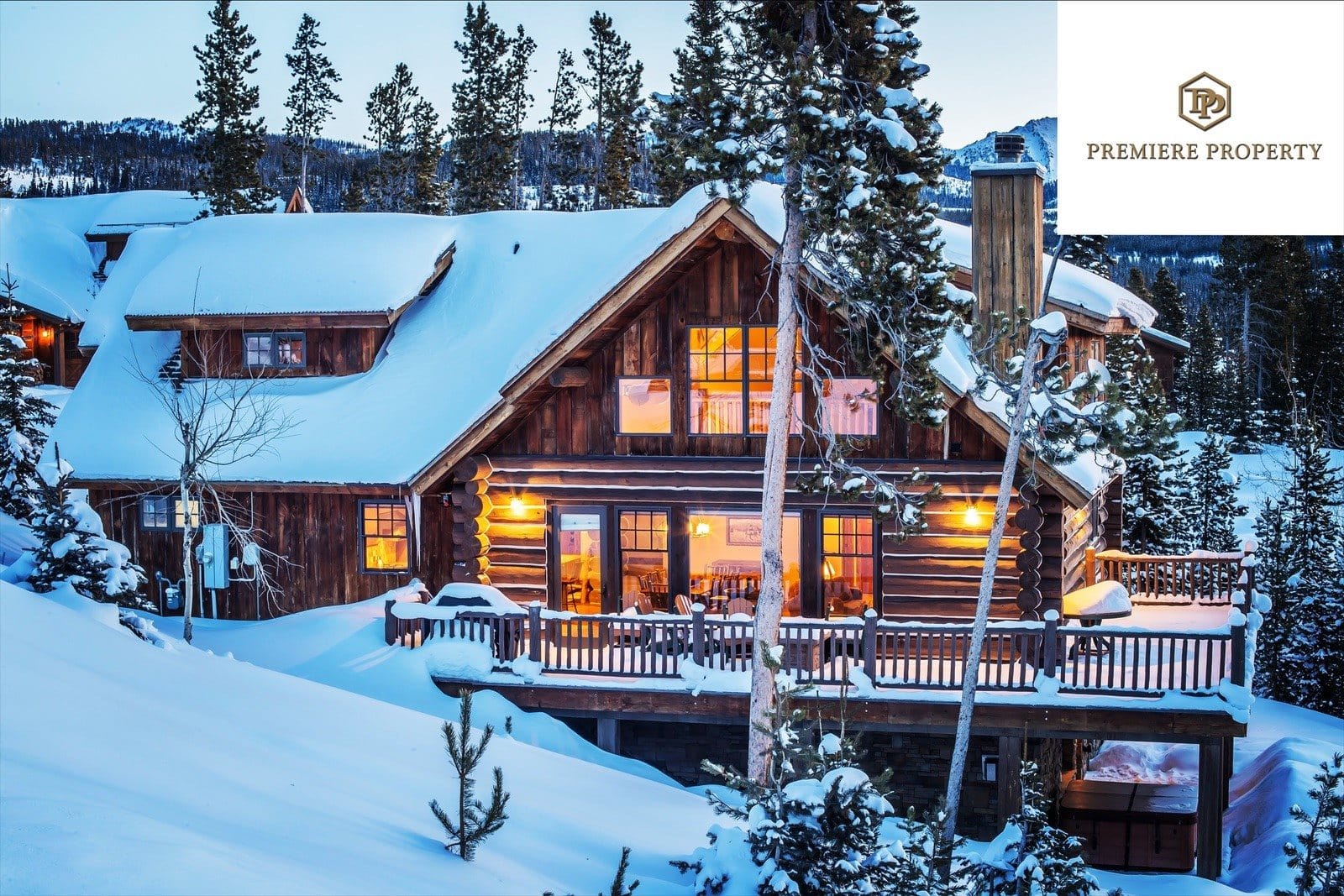 Snow-covered log cabin with lights on.