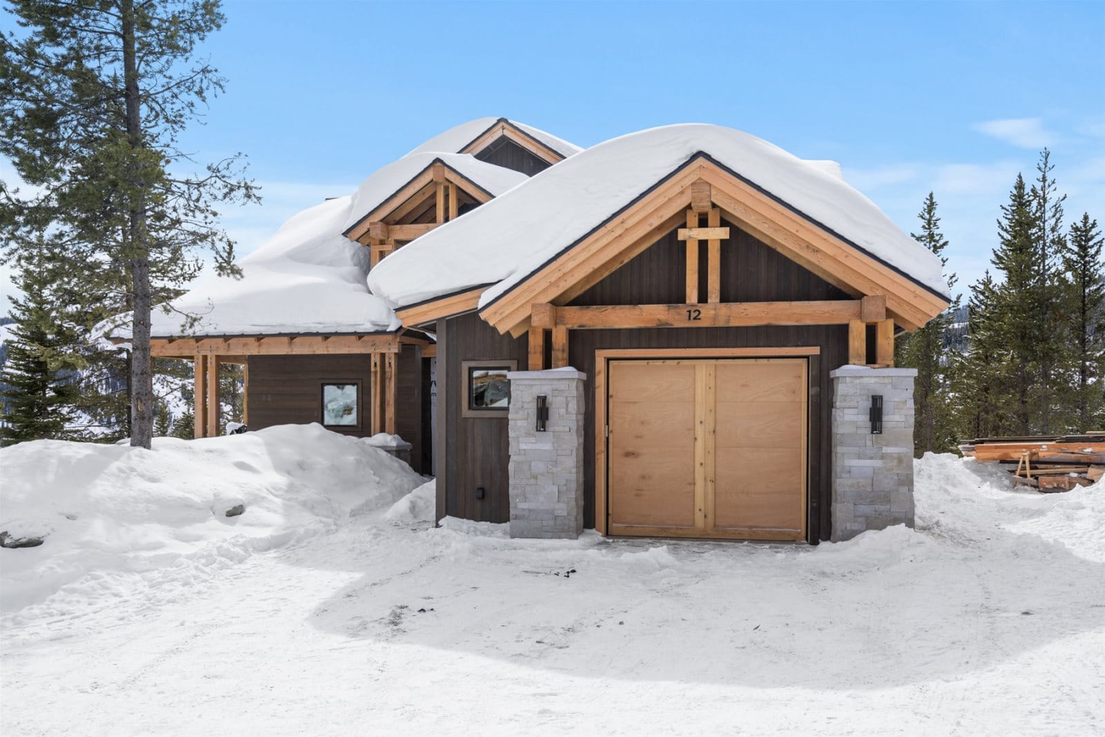 Snow-covered cabin with wooden garage.