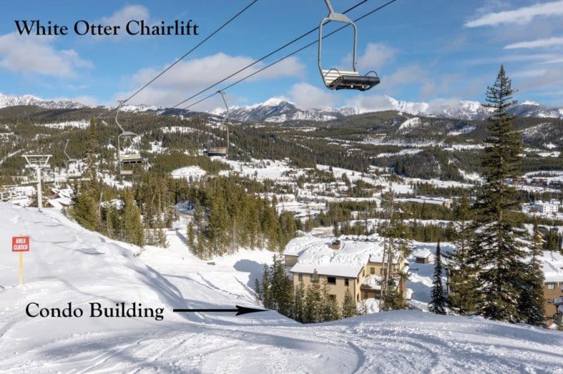 Snowy landscape with chairlift and condos.