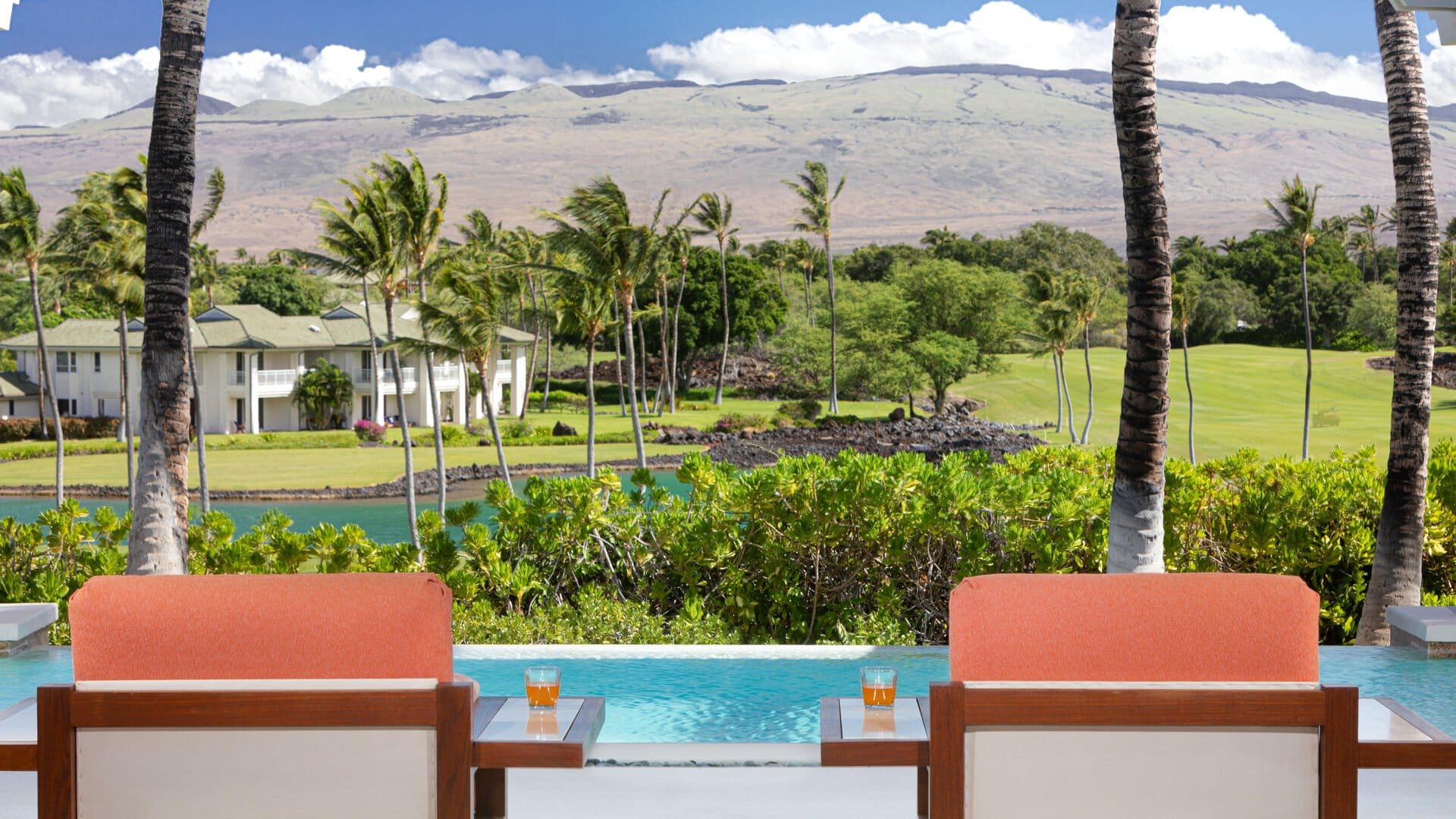 Poolside chairs overlooking scenic landscape.