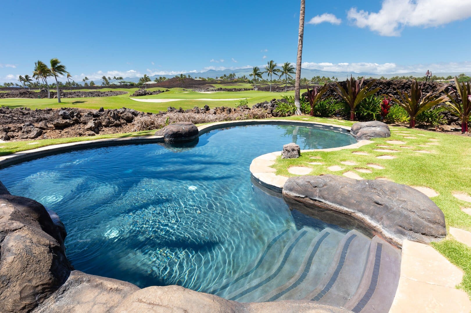 Rock-bordered pool with golf course.