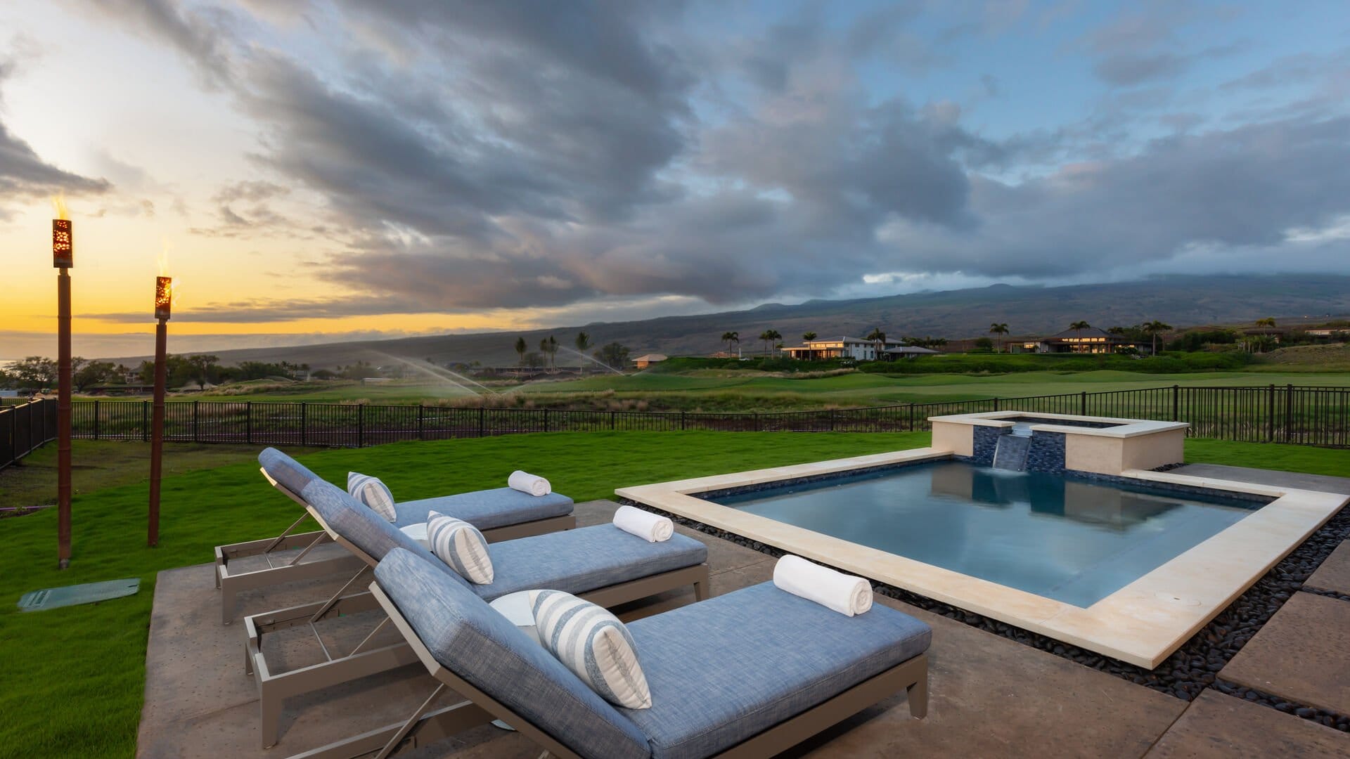 Poolside lounge chairs at sunset.